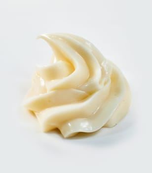 Elegant twirl of creamy homemade mayonnaise in a close up side view over white