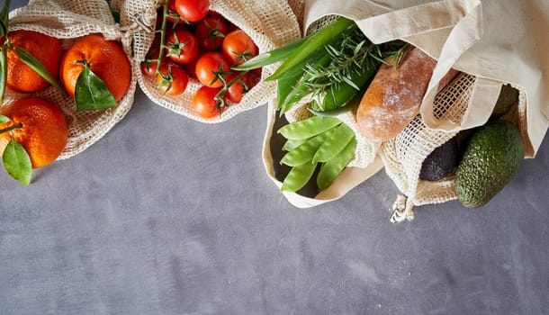Fabric bags with fresh organic groceries from local market. Eco-friendly packing shopping concept with grey copy space