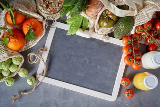 Fresh organic groceries packed in eco-friendly reusable fabric bags. Recipe or menu layout concept with white frame on grey background, viewed from above
