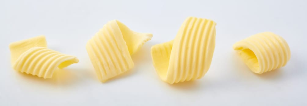 Set of different butter curls or rolls in a row in close-up on white surface background