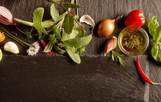 Set of spices and herbs in kitchen layout, viewed from above on dark stone table with copy space