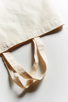 Unlabeled empty reusable eco-friendly fabric bag for groceries shopping, viewed in close-up from above on white background