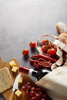 Groceries for a pub style lunch with red wine in a natural fiber reusable shopping bag to reduce use of plastic