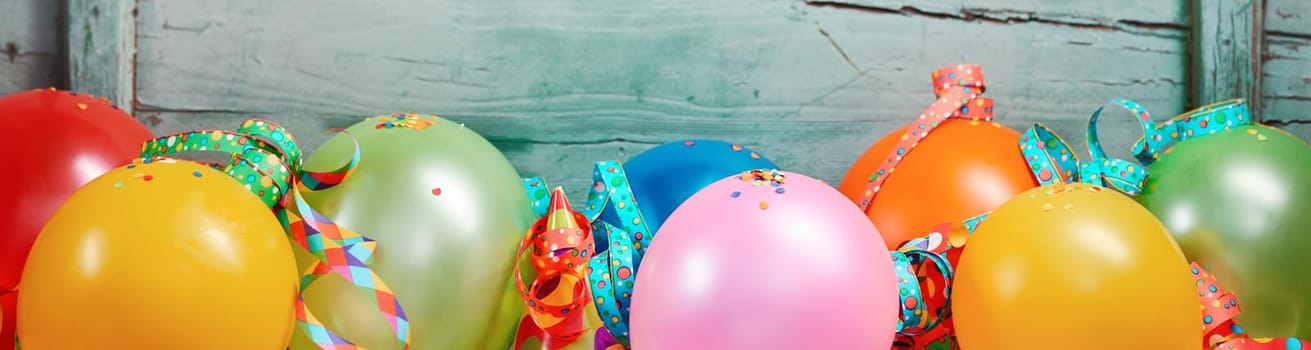 Festive banner with a row of colorful balloons and ribbons in a row against old wooden background