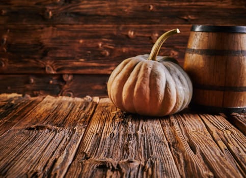 Pumpkin and barrel on old wooden table with aged wood grain surface inside rustic house. Copy space