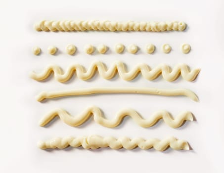 Decorative wavy lines and dots of mayonnaise piped from a tube on a white background for food styling elements