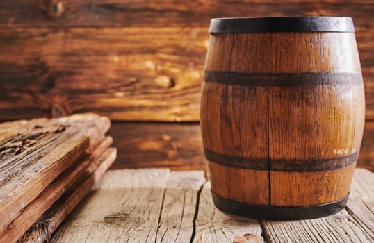 Lacquered barrel on old wooden boards surface with copy space, inside rustic house or bar
