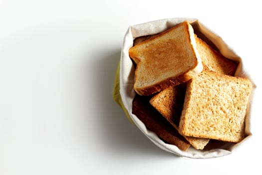 Fried toast bread slices put in white bag, and viewed from above on white background with shadow. Copy space