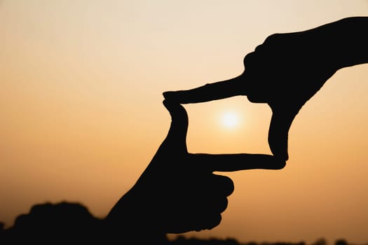 Hands making frame with sunset. Close up of woman hands making frame gesture.