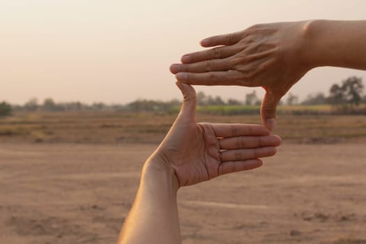 Hands making frame with sunset. Close up of woman hands making frame gesture.