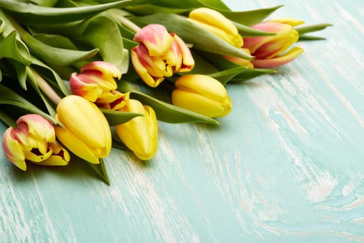 Beautiful bouquet of tulips on a green wooden background with copy space. Top view.