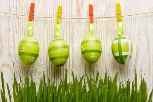 Colored easter eggs and spring green grass on a wooden background. Greeting card.