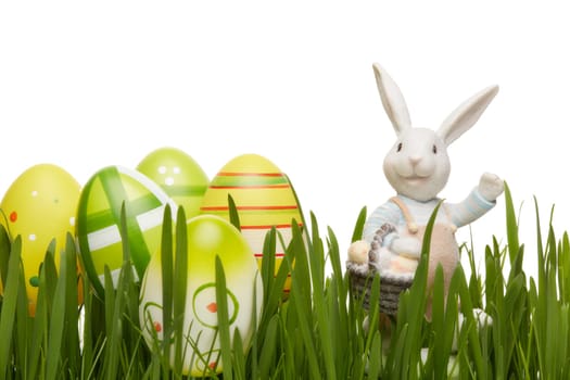 Colored easter eggs, easter rabbit and spring green grass on a white background. Greeting card.