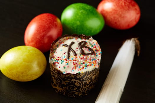 Still life with easter cake, colored eggs and Jerusalem church candles ( bunch of 33 candles ) lying on black wooden background.