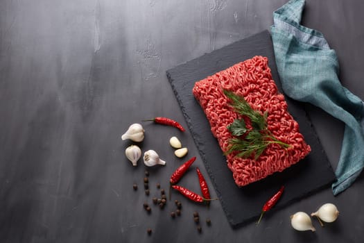 Still life with fresh forcemeat from beef and spices on a dark background. Top view with copy space