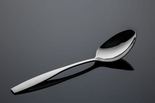 Stainless steel metal spoon on a reflective surface