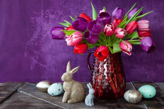 Colorful tulips in spring with easter decorations in front of purple background