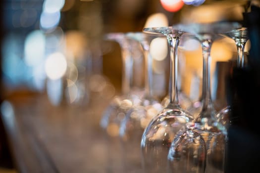Close-up of a large group of empty wine glasses on a bar counter.