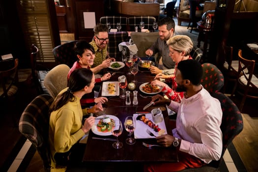Small group of friends enjoying a meal in a restaurant. They are sitting at a table as they eat their food.