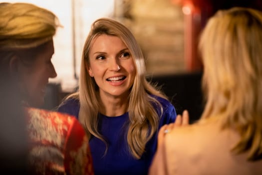Over the shoulder view of a mature woman talking and smiling with her friends.