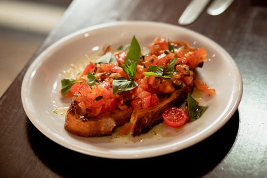 Restaurant style bruchetta on a plate on a wooden table in a restaurant.