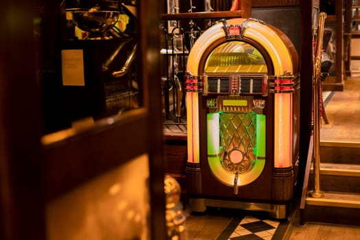 Retro jukebox in the corner of a restaurant by a set of stairs.