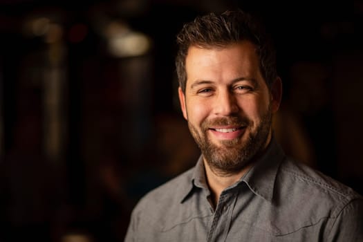 Headshot of a mid adult man smiling and looking at the camera.
