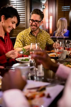 Friends catching up over a meal in a restaurant. They are smiling and talking while enjoying their food.