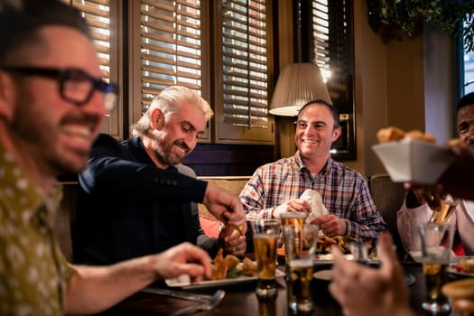Small group of mid adult men enjoying some food in a restaurant.