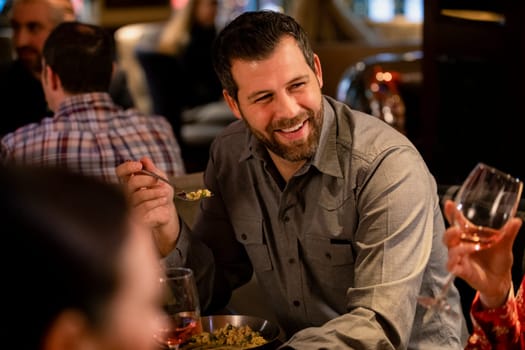 Mid adult man enjoying food while in a restaurant with some friends.