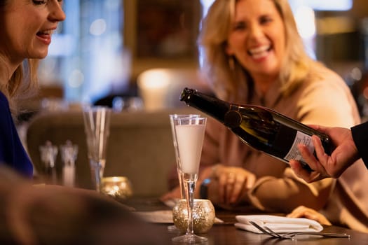 Close-up of a unrecognisable waiter pouring a glass of prosecco.