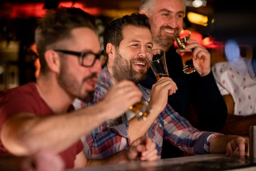 Three mid adult male friends enjoying a beer together in a bar.
