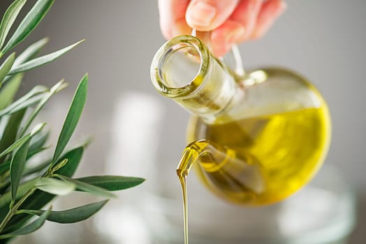 Bottle of virgin olive oil pouring close up