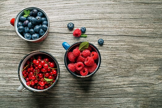 Mix of fresh berries in a bowls on wooden background