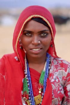 Young indian woman portrait wearing traditional sari, jewellery and a red veil, Thar Desert, Northern India