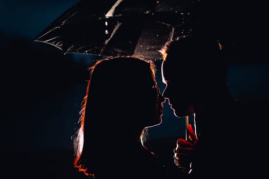 young man and woman under an umbrella and rain.