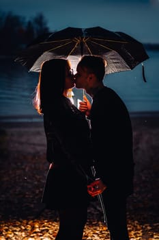 young man and woman under an umbrella and rain.