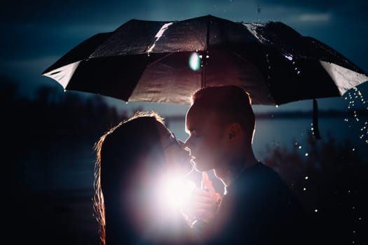 young man and woman under an umbrella and rain.