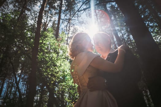 bride and groom on the background of trees and forest sun.