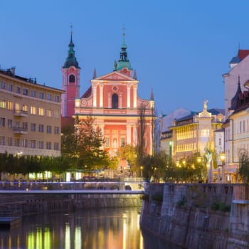 Romantic medieval Ljubljana's city center, capital of Slovenia, Europe. Night life on the banks of river Ljubljanica where many bars and restaurants take place. Franciscan Church in background