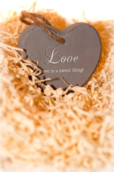single brown wooden love heart in a love nest made of straw inscribed  love is a sweet thing