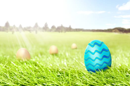 Colorful easter eggs hidden in the grass field with trees and blue sky background. Happy Easter
