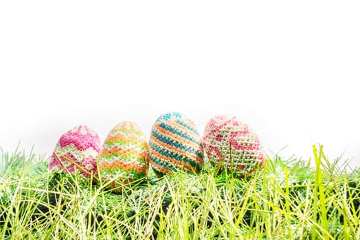 Colorful easter eggs on the green grass over white background. Happy Easter