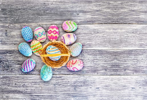 Colorful easter eggs in the nest on wooden basket and wooden table. Happy Easter