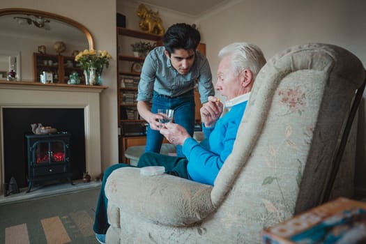 Teenage boy is giving his grandfather his medication.