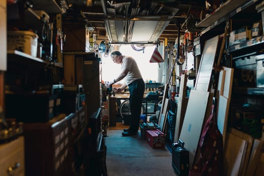 Senior man is working in his shed on a woodwork project. He is fatsening something in to a vice.