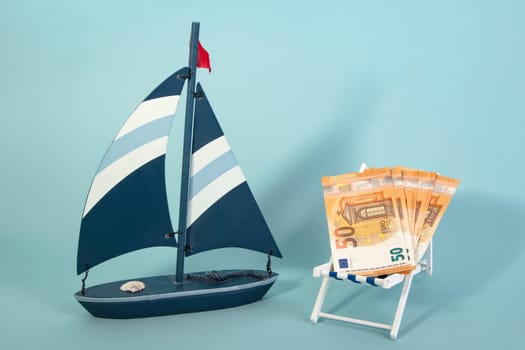 Summer Vacation Concept with toy boat with fifty Euro Banknotes on blue background