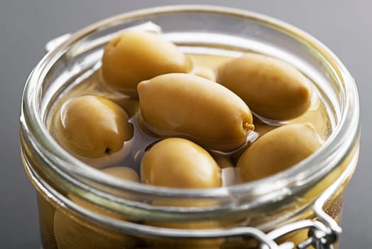 Pickled green olives in glass jar close up