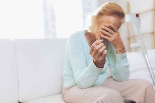 Heartbroken elderly woman holding he husbands wedding ring