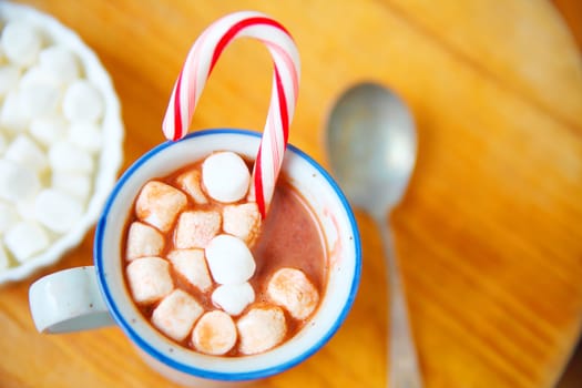 Overhead of cocoa with marshmallows and candy cane